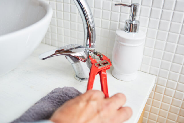 Plumber's,Hand,Using,Pipe,Wrench,While,Installing,A,Sink,Faucet